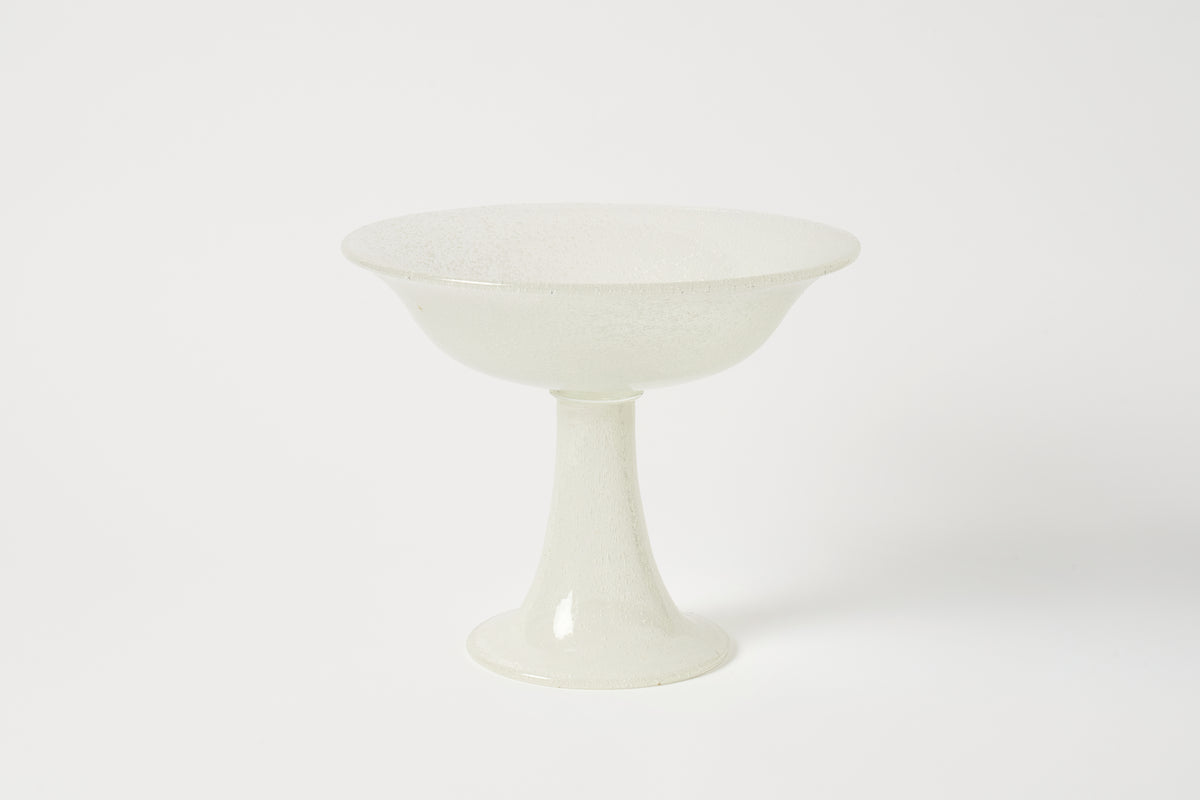 A white glass pedestal bowl with a textured, crackled surface, set against a plain white background.
