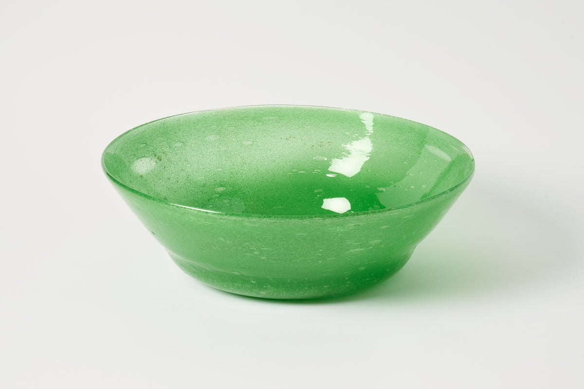 A translucent green glass bowl with a textured, hand-blown finish, photographed on a seamless light gray background.