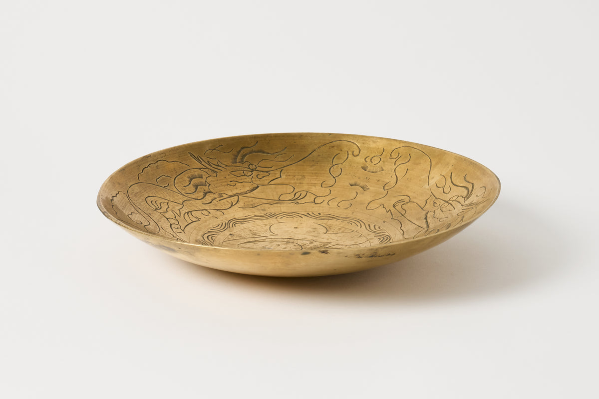 A round brass plate with engraved dragon motifs, displayed on a clean white background.