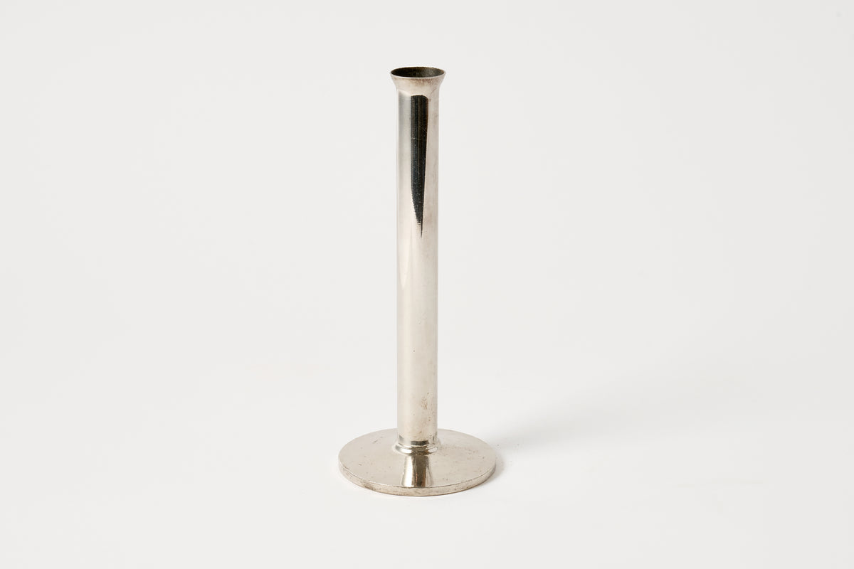 A polished silver metal candlestick holder with a cylindrical stem and a circular base, photographed against a clean white background.