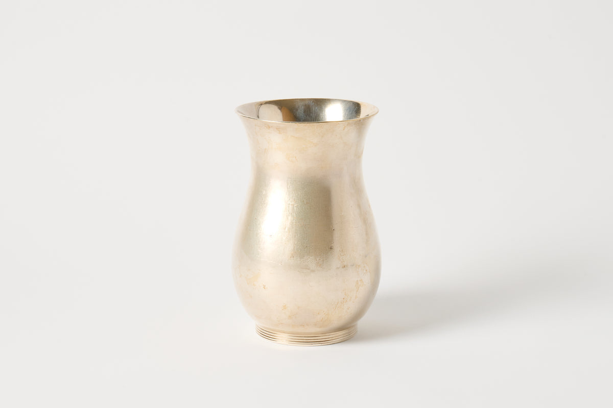 A small vintage silver-toned vase with a flared rim, shown on a plain light gray background.