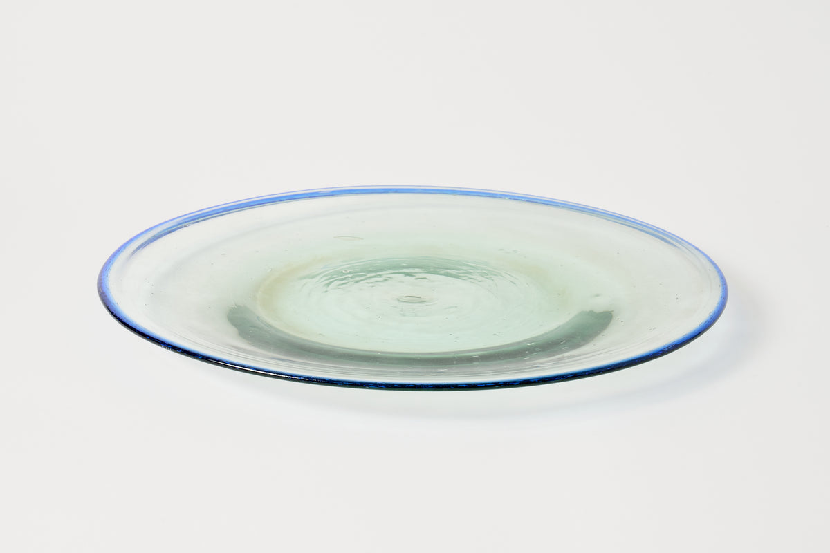 A round clear glass platter with a thin blue rim, photographed on a clean white background.